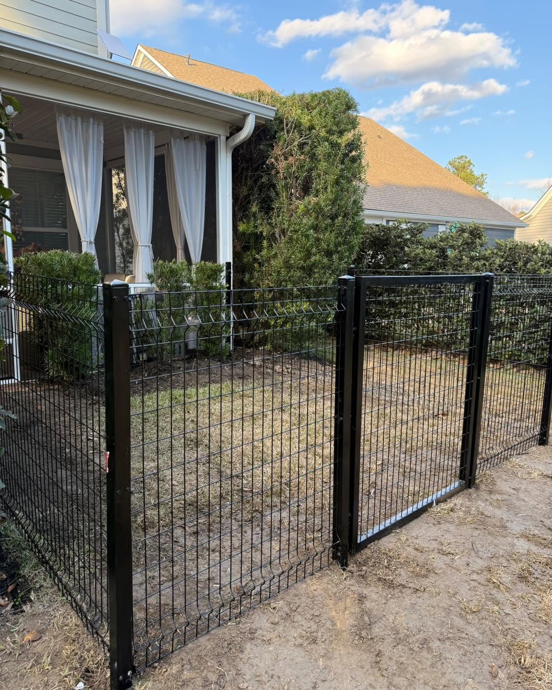 Black welded wire fence with gate beside a porch