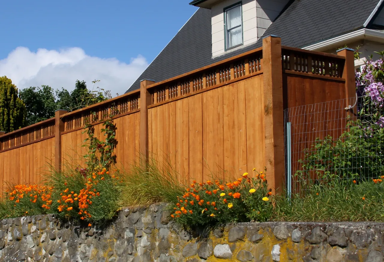 Cedar fence with lattice top above a stone wall